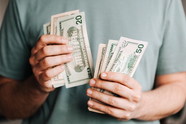 person in teal shirt counting money